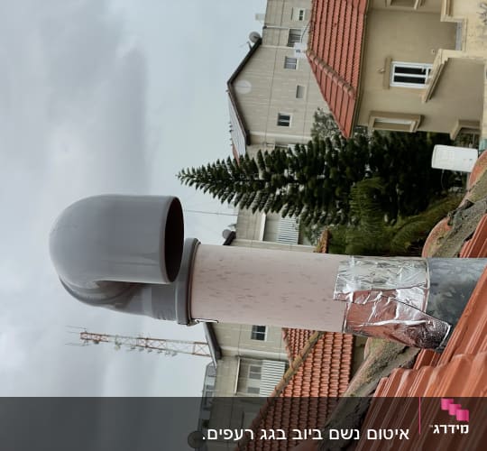 צינור אפור על גג רעפים אדום עם סרט כסף